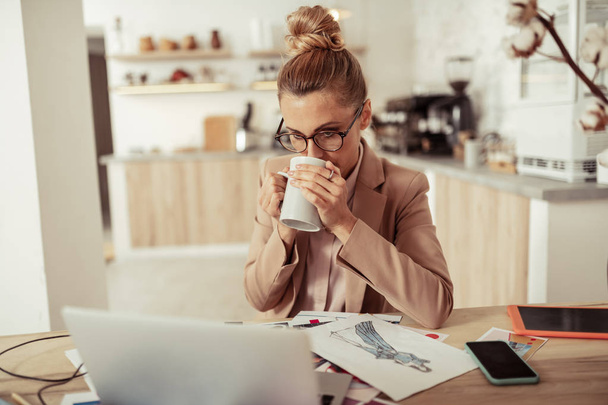Fashion designer drinking coffee at her workplace. - Foto, Bild