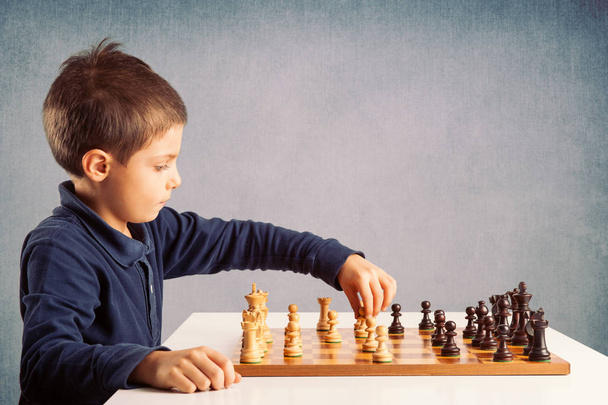 Kid playing chess on grunge background. - Foto, afbeelding