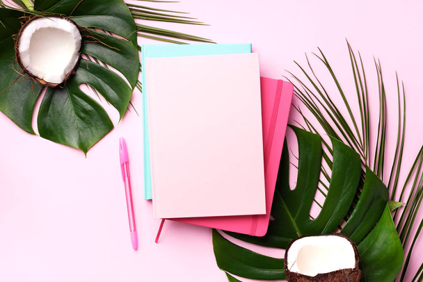 Green monstera, palm leaves, coconut, notebooks over pink background. Female blog writer workspace concept. Flat lay. Top view. - Foto, Imagem