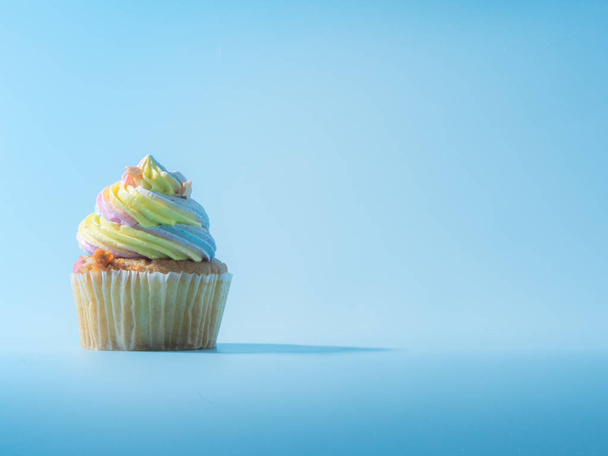 Colorful and enteresting cupcake isolated on blue background studio close up shot. - 写真・画像