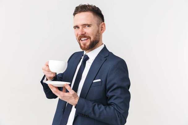 Happy businessman posing isolated over white wall background drinking coffee. - Foto, Bild