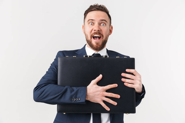 Excited businessman posing isolated over white wall background holding bag case. - Zdjęcie, obraz