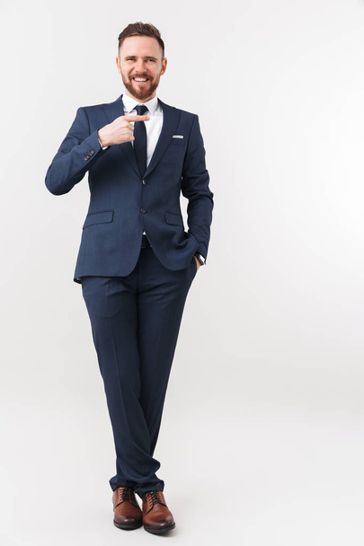Handsome young businessman posing isolated over white wall background pointing. - 写真・画像
