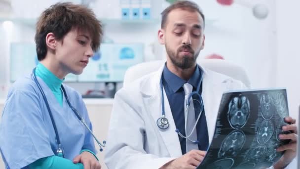 Medical scientist with a nurse in modern office looking at MRI and CT scans - Séquence, vidéo
