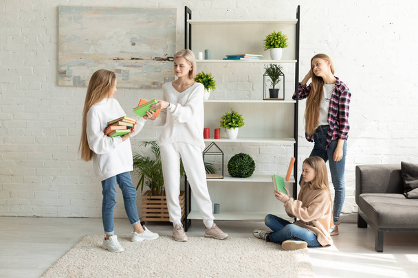junge attraktive lesbische Familie in lässiger Kleidung verbringt Zeit miteinander im Wohnzimmer - Foto, Bild