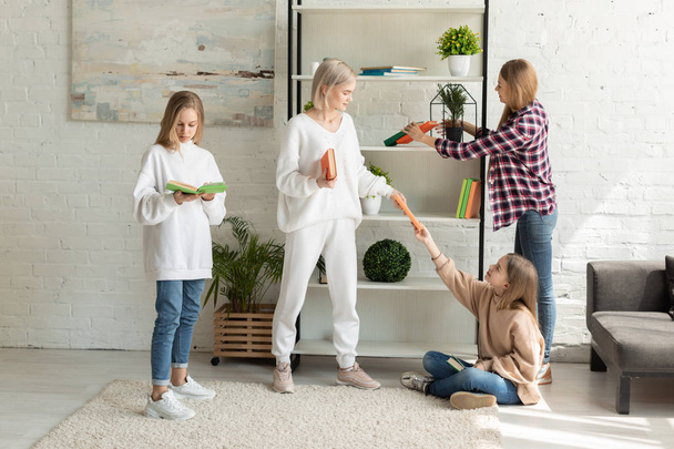 junge attraktive lesbische Familie in lässiger Kleidung verbringt Zeit miteinander im Wohnzimmer - Foto, Bild