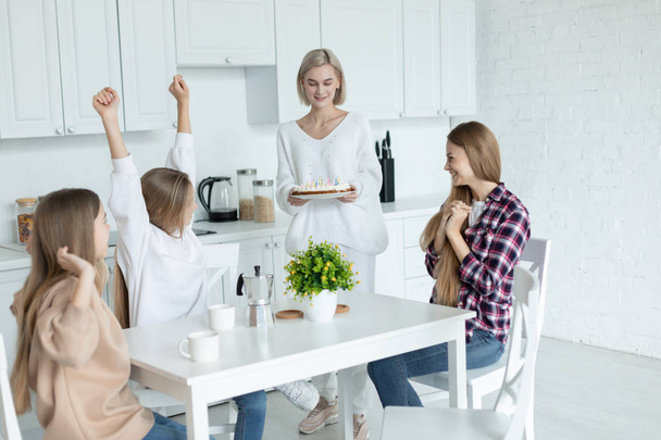Happy young lesbian family celebrating birthday of their daughter in the kitchen at home - Foto, Bild