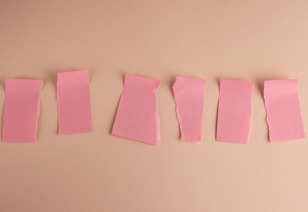  pegatinas de papel rosa pegadas en la pared y rasgadas por la mitad
  - Foto, imagen