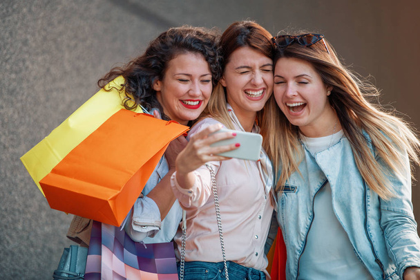 Kolme kaunista nuorta naista ostoskasseineen kaupungissa.Myynti, muoti, kulutus ja ihmiset käsite
 - Valokuva, kuva