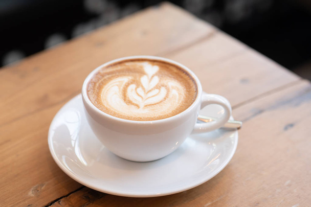 coffee latte in a white cup on wooden table in coffee shop. - Fotoğraf, Görsel
