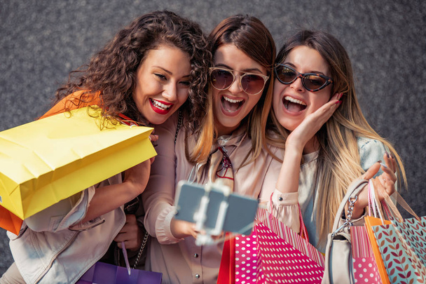 Tres hermosas mujeres jóvenes con bolsas de compras en la ciudad.Venta, moda, consumismo y concepto de personas
 - Foto, imagen