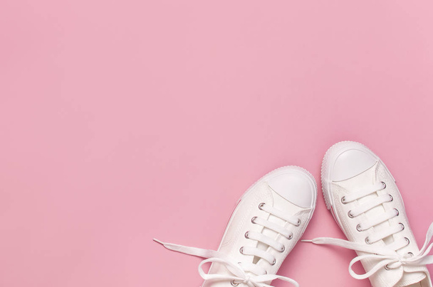 White female fashion sneakers on pink background. Flat lay, top view, copy space. Women's shoes. Stylish white sneakers. Fashion blog or magazine concept. Minimalistic shoe background, sport shoes - Fotó, kép