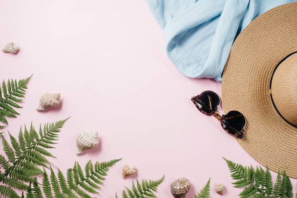 Vrouwelijke zomer mode samenstelling met blouse, hoed, zonnebril, Fern, Seashell op roze achtergrond. Platte lay, Top uitzicht minimalistische kleding collage. Reizen vakantie concept. Zomer achtergrond. - Foto, afbeelding