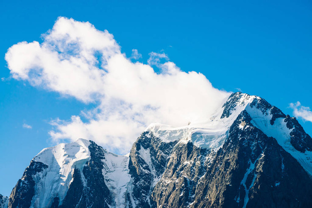 Καταπληκτικό παγετώνα κάτω από τον γαλάζιο ουρανό. Τεράστιο σύννεφο σε γιγαντιαία υπέροχα χιονισμένα βουνά στο φως του ήλιου. Ατμοσφαιρικό μινιμαλιστικό ορεινό τοπίο της μεγαλειώδης φύση στην ηλιόλουστη μέρα. - Φωτογραφία, εικόνα