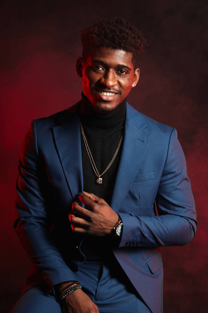 Young dark-skinned entrepreneur in formal clothing, standing against dark wall - Photo, image