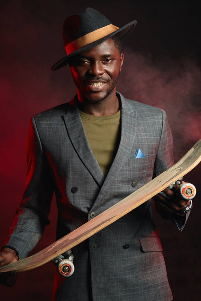 Young african handsome businessman with longboard in the office - Фото, зображення