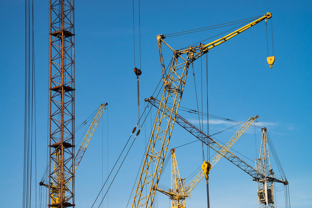 Big tower cranes against the blue sky. Background image of construction equipment close-up with copy space. Build of city. - Foto, Bild