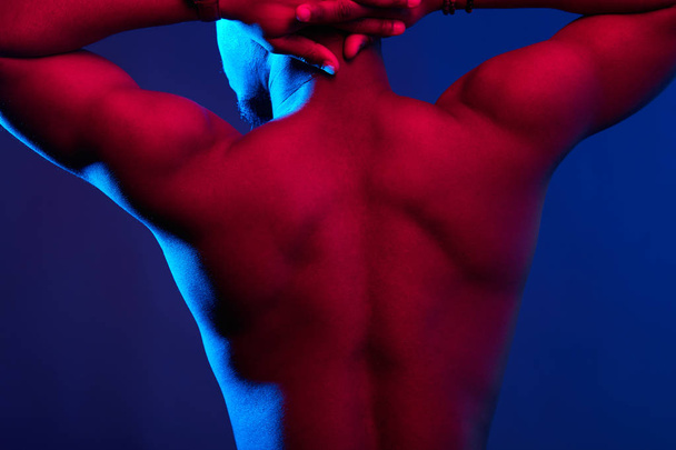 Rear view of African male athlete with naked back posing against dark wall. - Fotografie, Obrázek