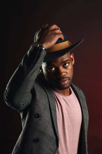 Afrikai üzletember szürke öltönyt és fekete kalapot a stúdióban a sötét háttér - Fotó, kép