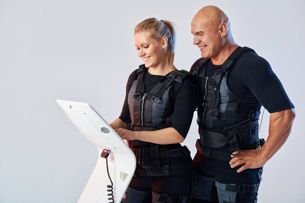 smiling cheerful man and woman training in EMS suit - Φωτογραφία, εικόνα