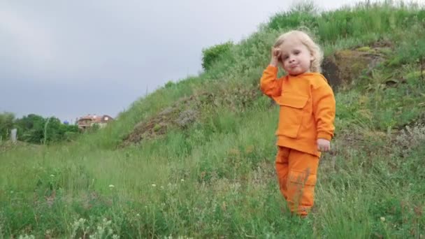 Маленький хлопчик в помаранчевій худі працює на траві - Кадри, відео