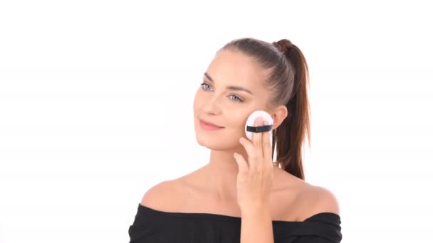 Beauty concept. A beautiful girl is applying a foundation powder on her face. - Záběry, video