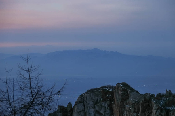 Monte tai no topo da montanha.Tai 'an, China - inverno 2017: vista do topo do monte tai, o topo do monte tai.Rocks e neve nos picos. Pinheiros no pico. As montanhas à distância loomed.Clouds wreathed it.The nuvens no céu eram grossas
 - Foto, Imagem