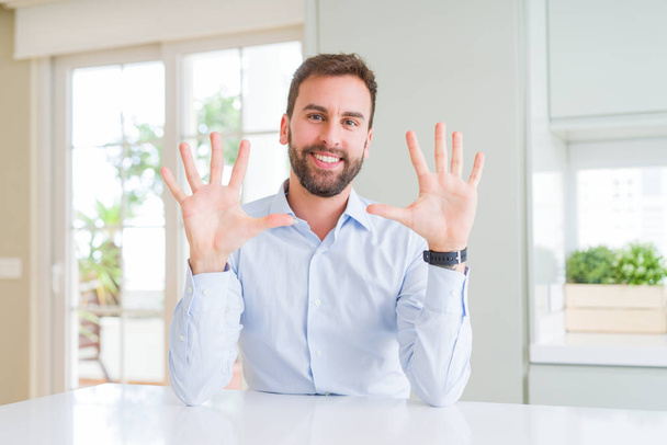 Pohledný obchodní muž ukazující a ukazující prsty číslo deset, zatímco se usmívá a věří. - Fotografie, Obrázek
