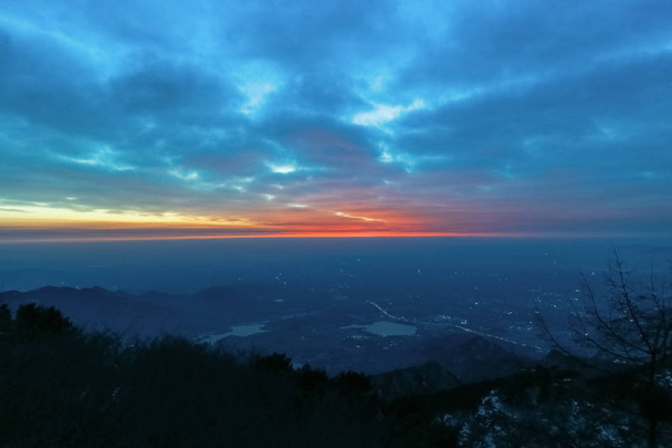 Vista do nascer do sol do monte tai.Tai 'an, China - inverno 2017: uma vista do topo do monte tai.The direção das montanhas.O brilho da manhã do nascer do sol.Nuvens surge, nuvens coloridas ao nascer do sol.O nascer do sol na horizonte.Com vista para a cidade eo lago
 - Foto, Imagem