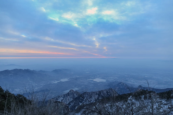 Góra Tai szczyty góry. Tai ' an, Chiny-zima 2017: widok z góry Tai Góra, Góra Tai. Skały i śnieg na szczyty. Sosny na szczycie. Góry w oddali. Chmury wiały go. Chmury na niebie były grube - Zdjęcie, obraz