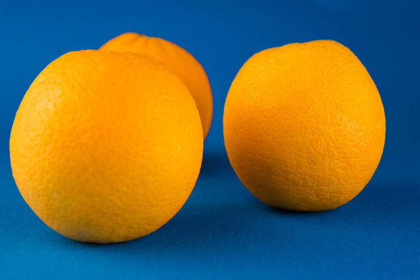 three whole oranges lying on a blue background - Fotoğraf, Görsel