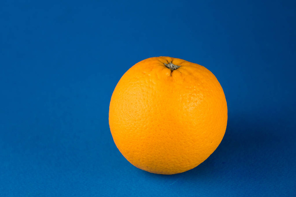 Closeup of one vibrant orange blood orange on light blue background with copy space - Valokuva, kuva