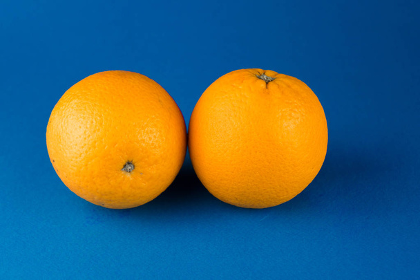 два апельсини, що лежать на синьому фоні
 - Фото, зображення