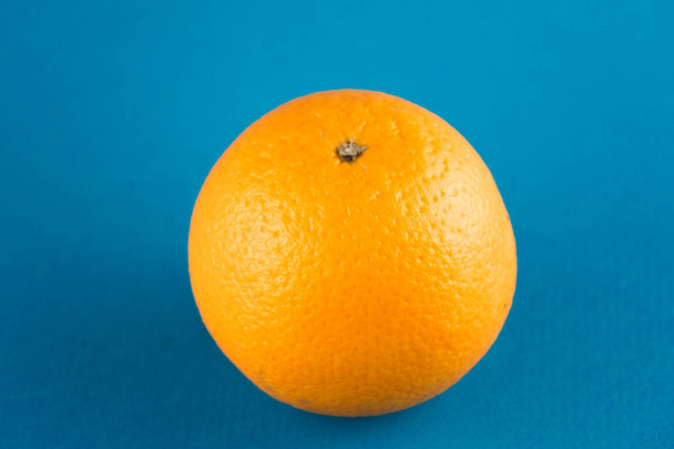 Nahaufnahme einer leuchtend orangen Blutorange auf hellblauem Hintergrund mit Kopierraum - Foto, Bild