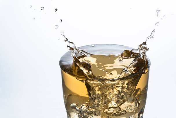 Zbliżenie kostki lodu rozpryskiwania na szklankę napoju bezalkoholowego Ginger Ale - Zdjęcie, obraz