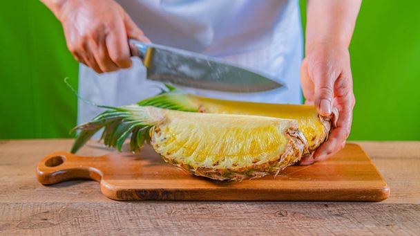 woman hands cutting fresh hawaiian pineapple on wooden table. - Фото, зображення