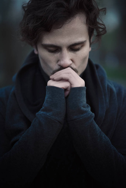 Handsome young curly man feels faith and hope. kisses his own hands - 写真・画像