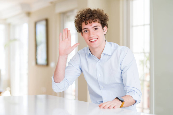 Young business man with curly read head Waiving saying hello happy and smiling, friendly welcome gesture - Photo, Image