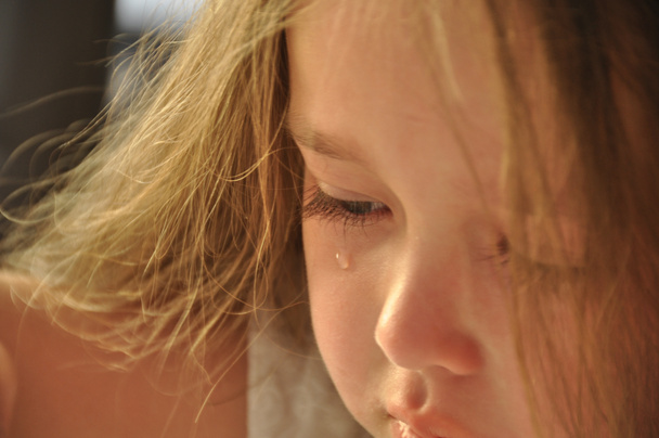 lágrima en la mejilla de una niña pequeña.Una niña pequeña, triste y molesta llorando una lágrima rueda por su mejilla
. - Foto, Imagen