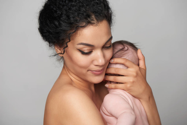 Pretty woman holding a baby in her arms - Фото, изображение