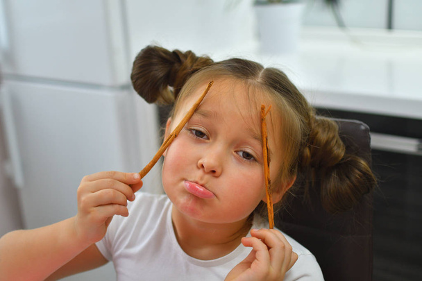 Girl holding and smelling cinnamon stic. Girl grimacing with cinnamon sticks. - Photo, Image