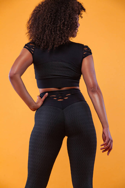 Back of strong athletic woman with black skin and curly hair, doing exercise on white background wearing sportswear. Fitness and sport motivation. - Valokuva, kuva