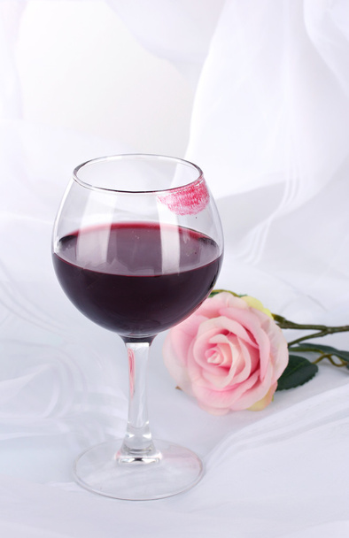 Glass of wine with lipstick imprint on white fabric background - Foto, afbeelding
