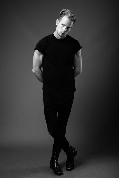 Estudio de un joven hombre guapo con camisa negra sobre fondo gris en blanco y negro - Foto, Imagen