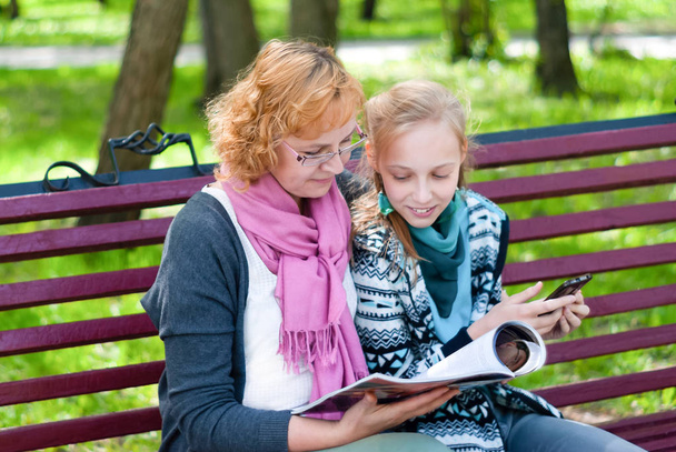 Mutter und Tochter lesen im Park eine Zeitschrift - Foto, Bild
