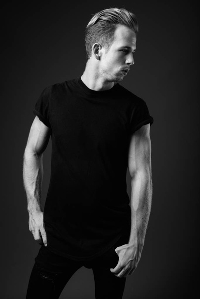 Студийный снимок молодого красивого мужчины в черной рубашке на сером фоне в черно-белом - Фото, изображение