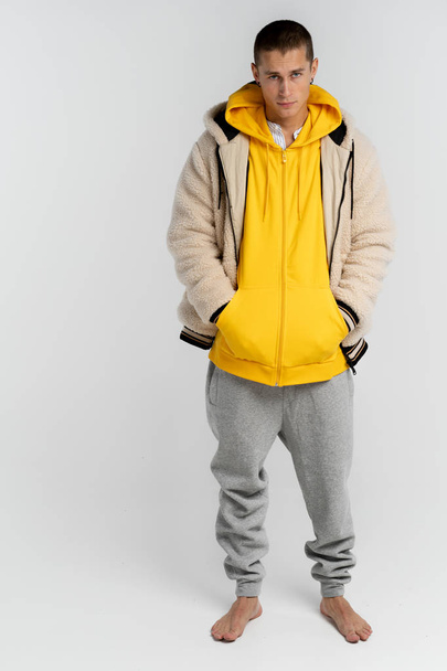 Portrait of serious attractive young man in yellow hoodie that looking at the camera isolated over white background - Photo, Image