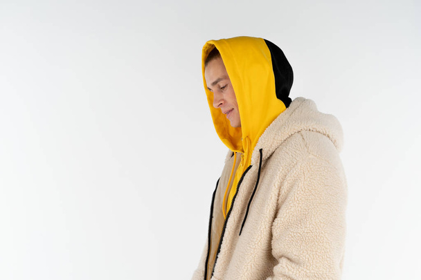 Half length portrait of young upset unhappy man wearing yellow hoodie standing against white background, copyspace for your text - Fotografie, Obrázek