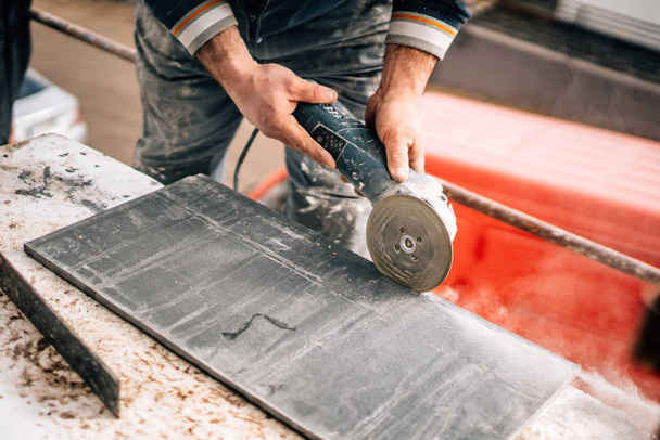 Construction site details - industrial tool, worker with angle grinder cutting marble and granite stone - Foto, afbeelding