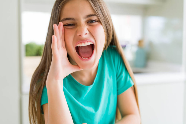 Gyönyörű fiatal lány visel zöld póló kiabálás és sikoltozik hangos mellé kezét a száját. Kommunikációs koncepció. - Fotó, kép